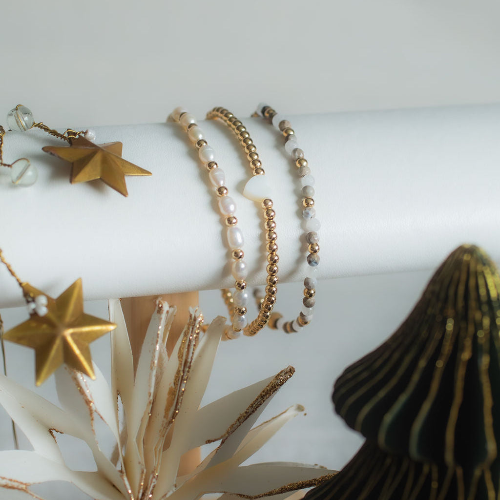 Gold bracelets on a white cylindrical stand with decorative elements.