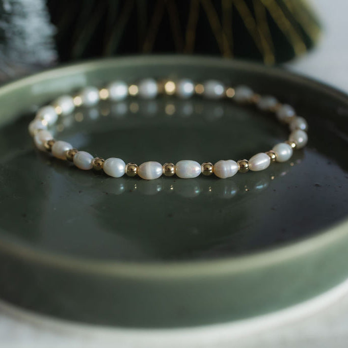Pearl bracelet on a green dish with a blurred background