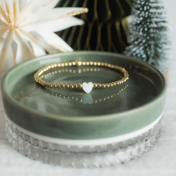 gold heart shaped bracelet on a green dish with christmas background