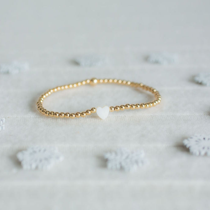 Gold bracelet on a light gray background with small decorative elements